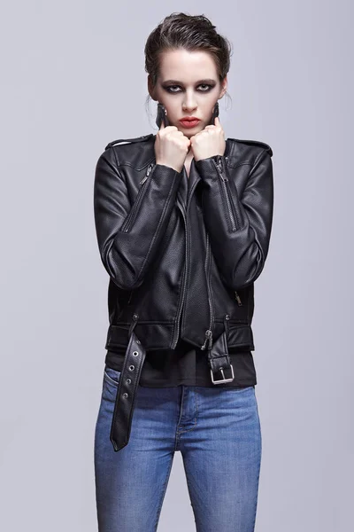 Portrait of female in black leather jacket. Woman with unusual beauty evening makeup. Girl with perfect skin, green pistachio colour eyes and violet - black shadows make-up.