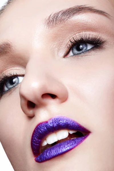 Closeup macro shot of human woman face makeup and bright violet