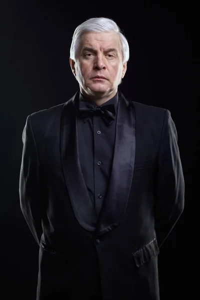 Mature icy calm man in black suit looking at the camera with a h