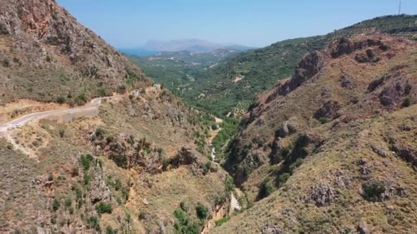 Letecký pohled z ptačí perspektivy video z dronu letu z kaňonu Topolia do horského údolí s olivovými háji a horskou vesnicí Topolia. Kissamos, prefektura Chania, Kréta, Řecko.