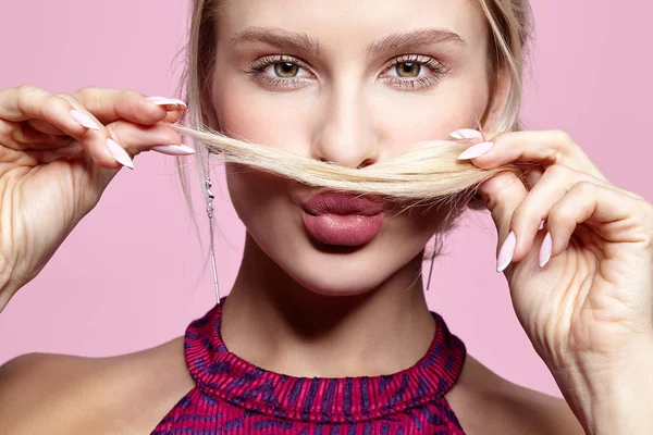 Young woman holds hair under nose like a mustache