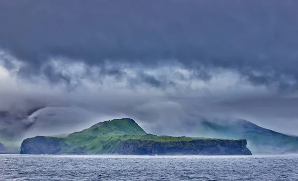 Coast of the Okhotsk sea. Surf and mountains covered in green forest