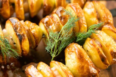 Domuz pastırmalı fırında patates, ahşap bir masada dereotu ve baharat.