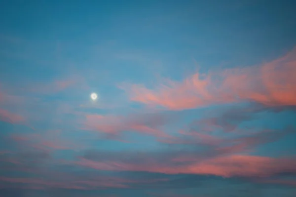 Bright sunset sky with clouds and moon