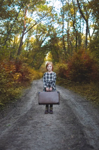 林道に両手でスーツケースを持つ少女 — ストック写真