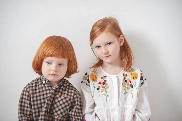 Red-haired children, brother and sister are sitting nearby