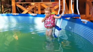 küçük kız havuzda yüzüyor.