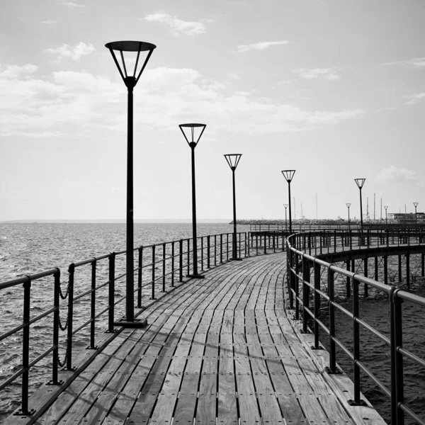 Perspective of promenade with street lights over the sea in Limassol, Cyprus. Black and white photography