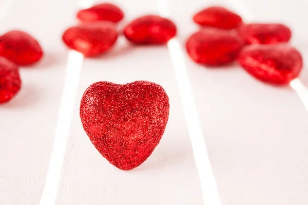 Birçok Beyaz ahşap zemin üzerinde kırmızı kalpler glitter. — Stok fotoğraf