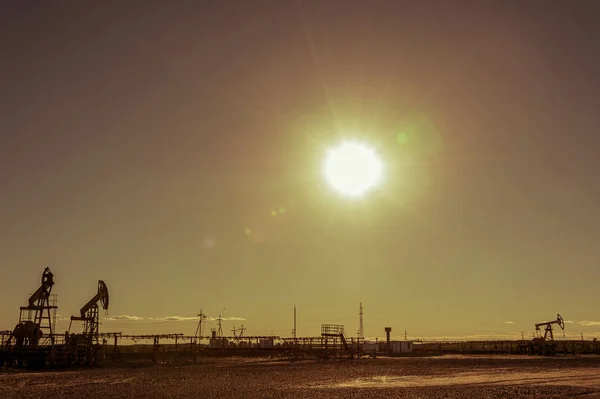 Ölpumpen im Ölfeld. Sommer heißer, sonniger Tag. Möwen schweben am Himmel. minimalistische Industrielandschaft. — Stockfoto
