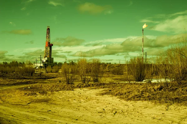 Paesaggio con un impianto di perforazione in un giacimento petrolifero. Giorno soleggiato, inizio primavera. Paesaggio industriale. Russia, Siberia occidentale . — Foto Stock