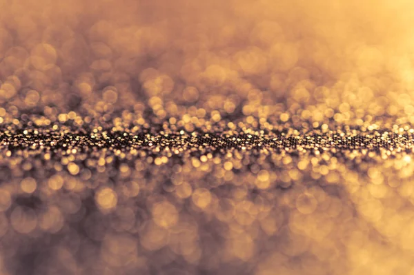 Abstract shiny golden background with bokeh and defocused lights. Glitter glowing texture pattern. — Stock Photo, Image