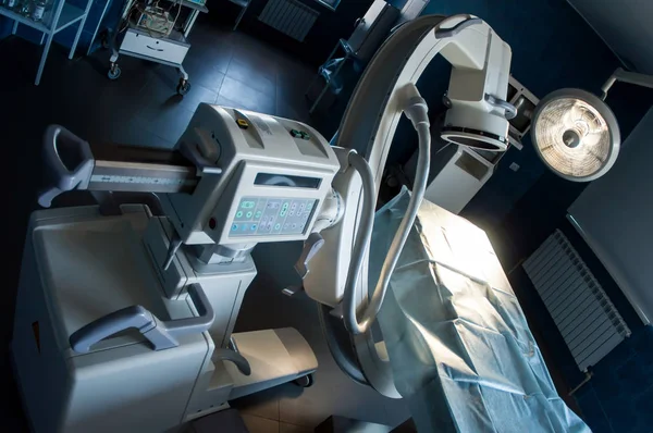 Moderner Operationssaal mit medizinischem Röntgenbild, Operationstisch, Speziallampe und medizinischen Geräten. Stockfoto