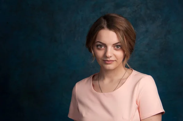 Portret van een jonge, aantrekkelijke vrouw met blond haar op een donkerblauwe achtergrond. — Stockfoto