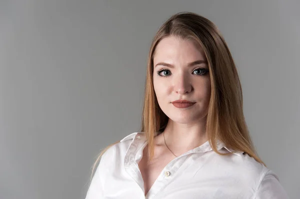 Retrato de uma jovem mulher atraente com cabelo loiro em um fundo cinza neutro . — Fotografia de Stock