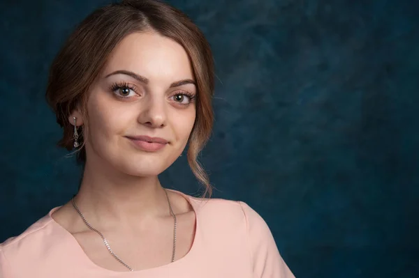 Portret van een jonge, aantrekkelijke vrouw met blond haar op een donkerblauwe achtergrond. — Stockfoto