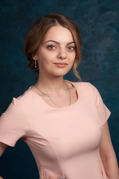 Retrato de uma jovem mulher atraente com cabelo loiro em um fundo azul escuro . — Fotografia de Stock