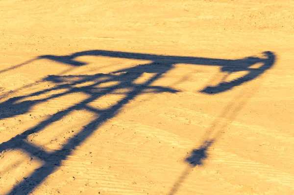 Oil pump shadow on dry ground. Oil and gas industry. Ecological problems concept. Global warming.