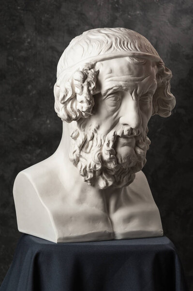 Gypsum copy of ancient statue Homer head on dark textured background. Plaster sculpture man face.
