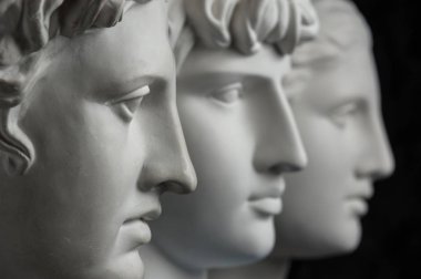 Antik heykel Apollo, Antinous ve Venüs baş alçı kopya koyu dokulu arka plan üzerinde. Alçı heykel yüz.