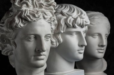 Antik heykel Apollo, Antinous ve Venüs baş alçı kopya koyu dokulu arka plan üzerinde. Alçı heykel yüz.
