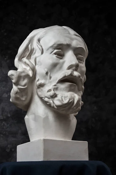 Copia de yeso de la antigua estatua de Juan el Bautista sobre fondo de textura oscura. Escultura de yeso hombre cara . —  Fotos de Stock