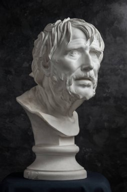 Gypsum copy of ancient statue Seneca head on dark textured background. Plaster sculpture man face. clipart