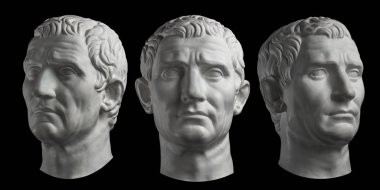 Guy Julius Caesar'ın eski heykel başının üç alçı kopyası siyah arka plan üzerine izole edilmiştir. Alçı heykel adam yüz.