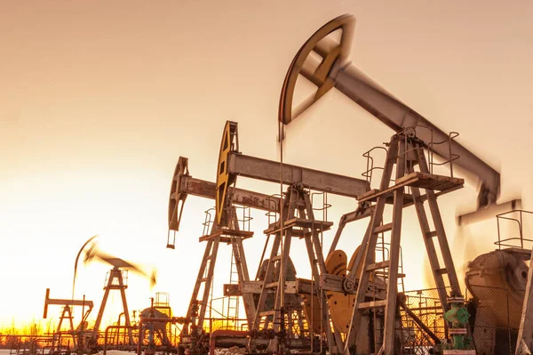 El Pumpjack de aceite contra un cielo al atardecer en el fondo. equipos industriales. Máquinas mecedoras para la generación de energía. Extracción de aceite. Guerra contra los precios del petróleo. Crisis global del coronavirus COVID 19 . —  Fotos de Stock