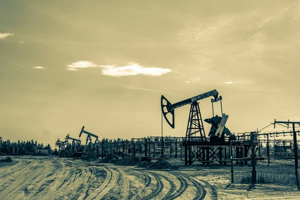 石油の概念。オイルポンプリグ。石油・ガス生産。油田地帯だ。ポンプジャックが走っている。化石燃料の産出と原油生産のための掘削区。世界的な危機。石油価格戦争. — ストック写真