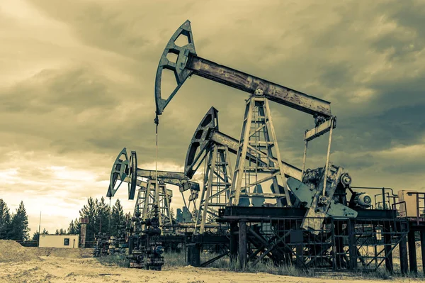 Concepto de petróleo. Plataforma de bomba de aceite. Producción de petróleo y gas. Sitio del campo petrolífero. Jack la bomba está funcionando. Drilling derricks for fossil fuels output and crude oil production. Crisis global. Guerra contra los precios del petróleo. —  Fotos de Stock