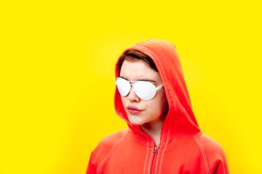 Kapüşonlu ve beyaz gözlüklü güzel bir kadının moda portresini kapat. Parlak sarı arka planda alternatif funky kız. Sıra dışı gençlik modası konsepti. Sıcak resim.