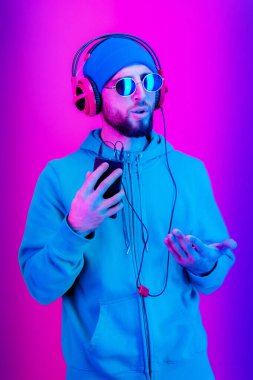 Gözlüklü, kulaklıklı, sakallı hippi dans ediyor ve akıllı telefonuyla zevkli müzikler dinliyor. Aşk canlı. Boş zaman hobisi konsepti. Rahatla..