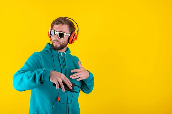 Funky jeune homme barbu hipster en lunettes et écouteurs danse et écoute de la musique agréable dans son smartphone. amour en direct. Loisirs hobby humeur concept. Détends-toi.. — Photo