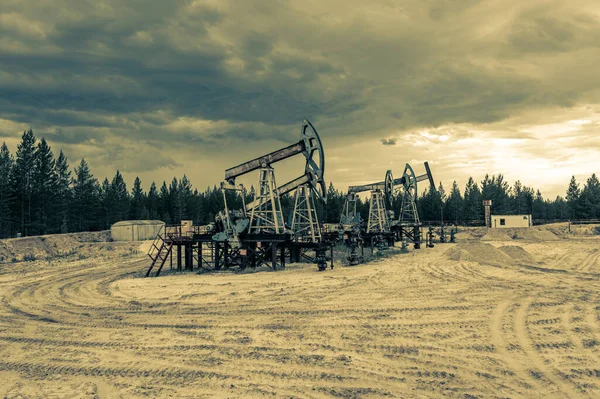 石油の概念。オイルポンプリグ。石油・ガス生産。油田地帯だ。ポンプジャックが走っている。化石燃料の産出と原油生産のための掘削区。世界的な危機。石油価格戦争. — ストック写真