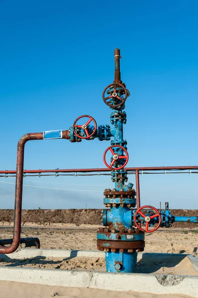 Uitrusting voor boorputten. Handklep met handwiel op de stroomleiding. Olieveld site. Olie, gas industrie concept. Industriële site achtergrond. Productie olie. Meervoudige terugslagklep armatuur. — Stockfoto