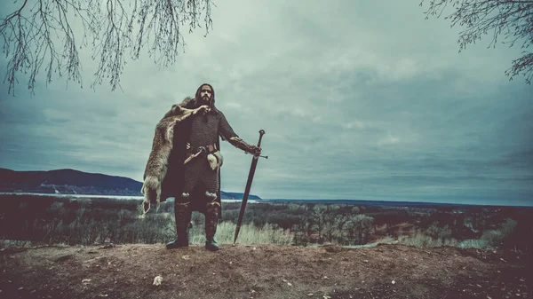 长头发的骑士用双手剑 中世纪农村背景 — 图库照片