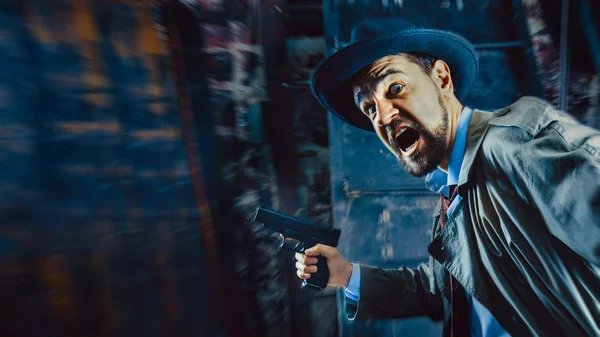 Detective con la pistola con un cappello da fedora e un trench, sfondo scuro . — Foto Stock