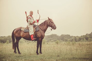 Etnik Giyim adam bir binicilik ve yay from hedefleyen.