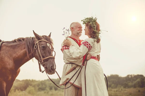 Mature man and woman in ethnic clothes are going to make a horse — Stock Photo, Image