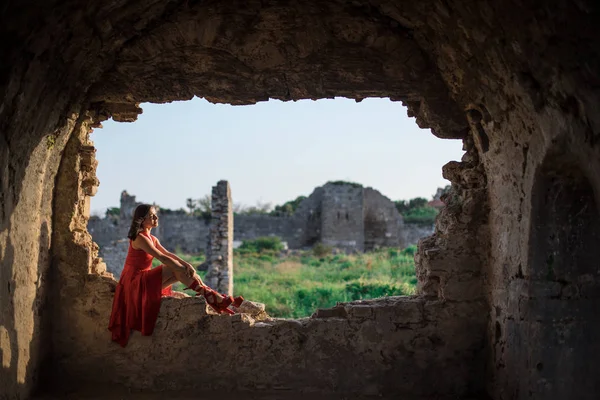 Woman in red dress is sitting at the ruins of an ancient city, Side, Turkey — Stock Photo, Image