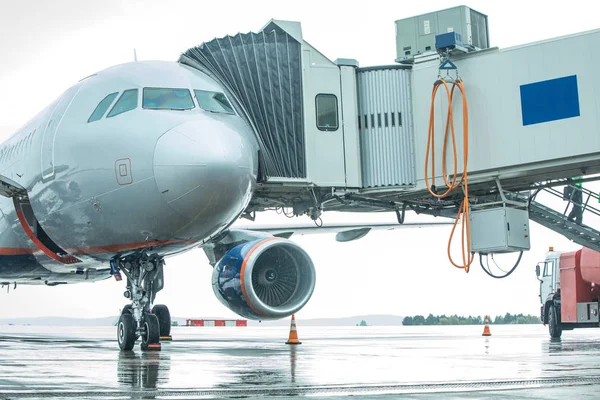 White unrecognizable airplane at the airport takes passengers through a telescopic ladder — Stock Photo, Image