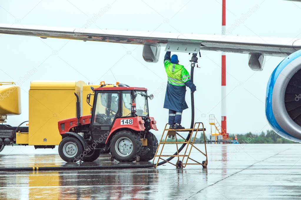 Aircraft refueling at the airport. Fuel tank and tractor on the background.