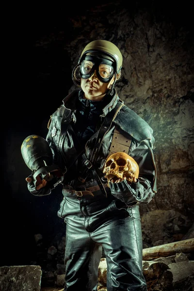 Soldier woman with the bomb in one hand and skull in another on the ruined background. — ストック写真