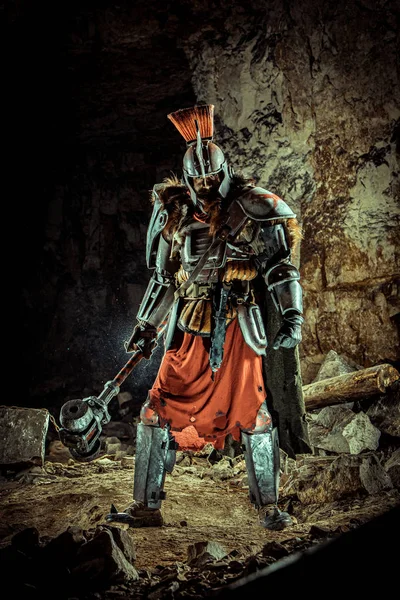 Powerful knight in the armor with the hammer. Dungeon on the background. — Stock Photo, Image