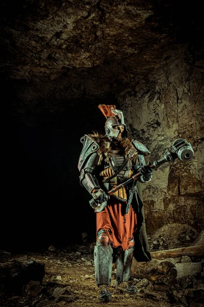 强大的骑士拿着铁锤在盔甲里 以地下城为背景. — 图库照片