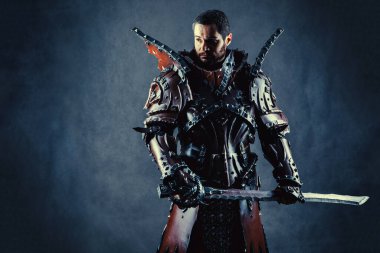 Kılıçlı, zırhlı güçlü bir şövalye. Koyu arkaplan.