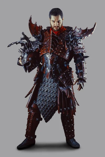 Elinde kaskla zırhlı güçlü bir şövalye. Gri arkaplan üzerinde izole.