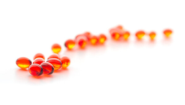 Красные таблетки на белой поверхности, вид вблизи
 