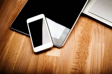 ahşap masa üzerinde telefon ve tablet pc ile dizüstü klavye